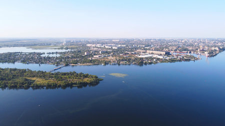 Drone fly over waving river surrounded by local village with various buildings and Wetland and marsh...