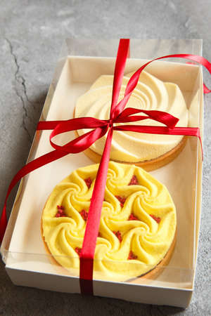Delicious mini tarts yellow and white with nuts and custard in the gift box. Assortment of delicious and colorful dessert, lemon curd tart, cream chocolate tart made by pastry chefの写真素材