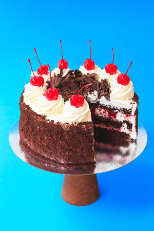 Sliced Birthday cake on the wooden cake stand. Beautiful chocolate sponge cake decorated with...