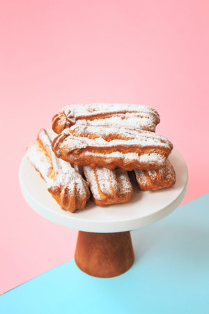Homemade eclairs with powdered sugar. Cream puffs filled vanilla custard and dusted with icing on a...