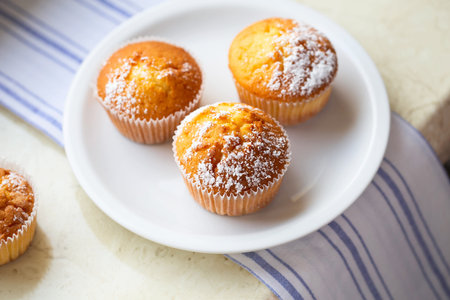 Sweet muffins with powdered sugar and blossoms. homemade bakery. Muffins in white capsules decorated...