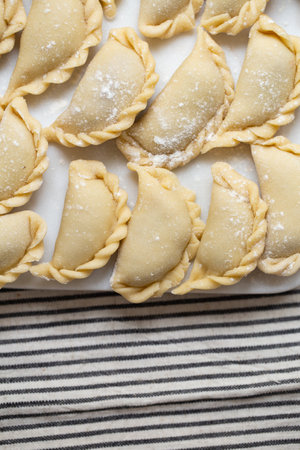 Fresh homemade dumplings prepared on a marble board, showcasing traditional handmade craftsmanship. Raw dough filled with savory ingredients, ready for cooking.の写真素材