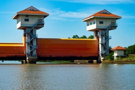 The orange dam in the river has a white tower that controls the opening of the dam.のeditorial素材