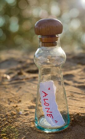 Message in glass bottle on sand with blurred bokeh backgroundの写真素材