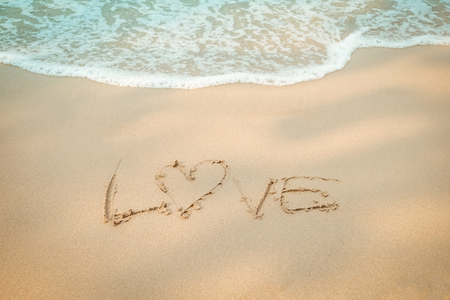 Love message hand writing on the sand beachの写真素材