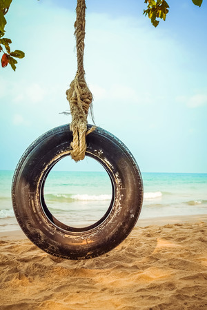 Old tyre swing on tropical beachの写真素材
