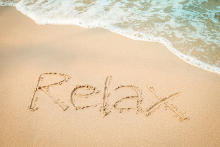 Relax message hand writing on the sand beachの写真素材