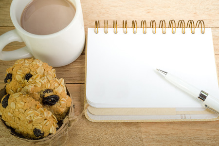 Blank notebook with coffee and oat cookies on wood backgroundの写真素材