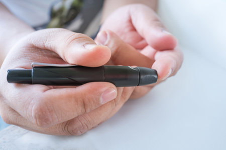 Close up of  male finger patient pricking his finger to draw a drop for blood testing