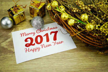 Merry christmas and happy new year message on white paper  with Christmas wreath and ornaments on wood backgroundの写真素材