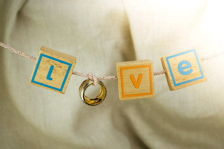 Love word from gold ring and small wood cube hanging on the rope, for love or valentine concept.の写真素材