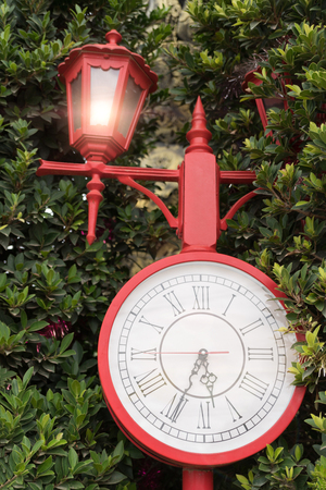 Antique red clock in the gardenの写真素材