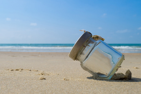 Empty glass bottle on sandy beach with blue sky and sea
の写真素材