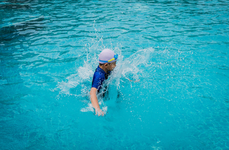 Portrait of young boy  jumping in the poolの写真素材