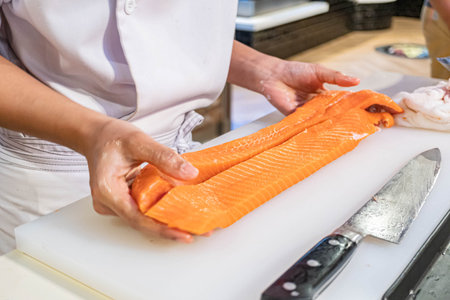 Chef preparing and cutting  fresh salmon in Japanese restaurant