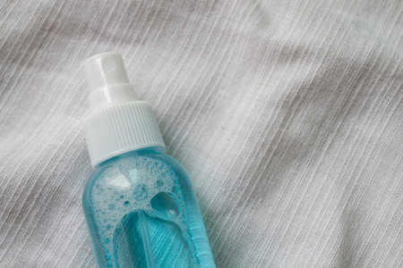 Alcohol spray bottle on a white fabric background