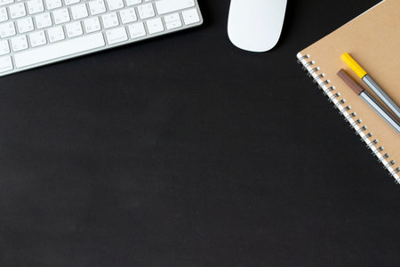 Modern black office desk table with keyboard and mouse and other supplies with Blank notebook page...