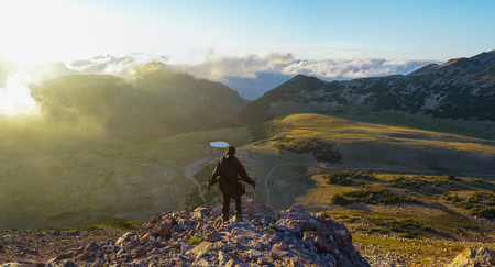 A hiker is standing on the mountain with clouds during sunset/sunrise at Mount Rainier National Park, Washington.の写真素材