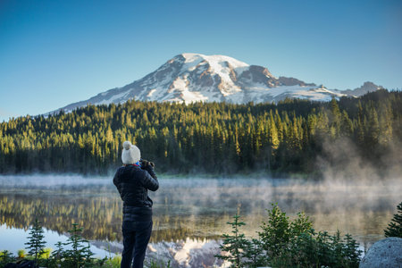 The woman photographer is taking pictures of the mountain and lake at Reflection Lakes and Mount...