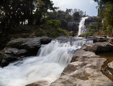 This is the photo of beautify giant waterfall surrounded with forrest and mountain and blue sky Wachirathan Falls in Chiang Mai, Thailandの写真素材