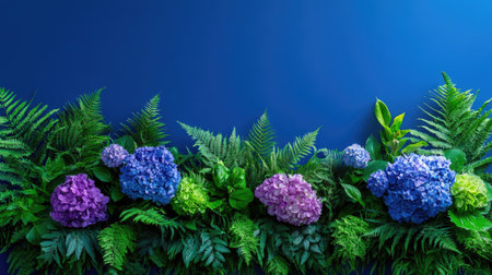 Dramatic contrast of hydrangeas and green ferns framed in rose-gold against blueの素材