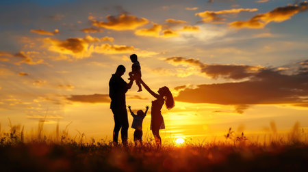 A heartwarming silhouette of a family enjoying a beautiful sunset in an open field. The image captures moments of love and joy shared among family members under a stunning sky.の素材