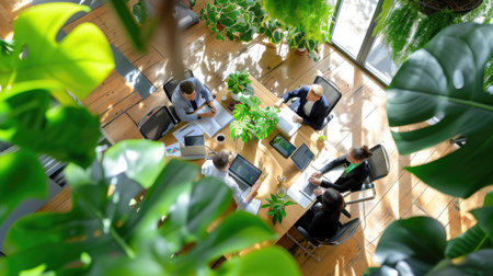 A vibrant team meeting takes place in a modern workspace filled with lush plants, natural light flooding in. Professionals engage in collaboration, showcasing innovative ideas.の素材
