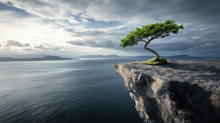 A solitary tree stands on a rugged cliff above a tranquil ocean, illuminated by the gentle light of sunrise, showcasing a captivating landscape.の素材