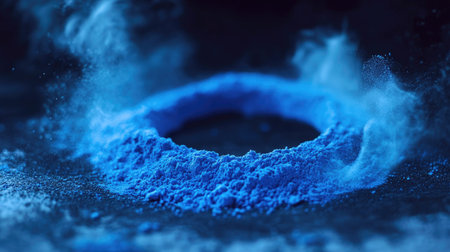 This image features a vibrant blue powder arranged in a circular shape, producing a captivating smoke effect against a dark background, ideal for artistic projects.の素材