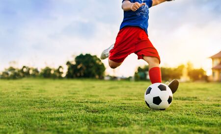 An action picture of a group of kid playing soccer football for exercise in community rural area under the sunset. Picture with copy space.の写真素材