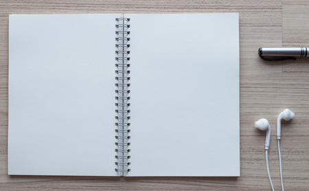 black pen, earplugs and open notebook on wooden.の写真素材