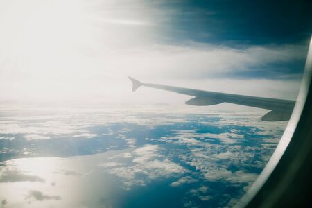 Clouds sky, sea and ray of light as seen through window of an aircraft. vintage filter.の写真素材