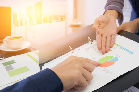 Business people negotiating a contract, they are pointing on a document and discussing together