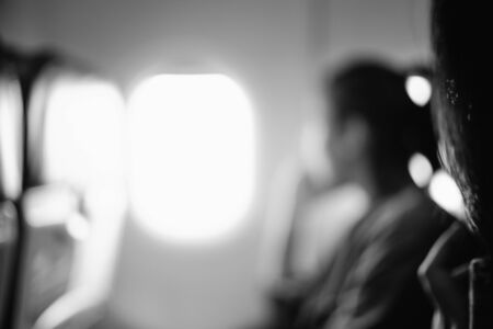 Abstract blur of woman looks out the window of an flying airplane. black and white filter effect