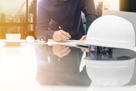 Image of engineer drawing plan on blue print in office near working site