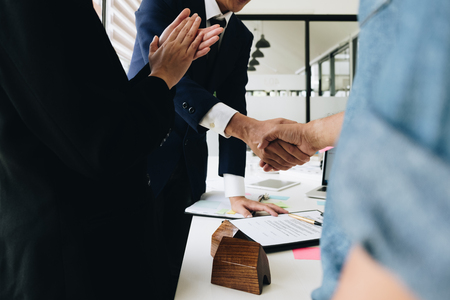 Estate agent shaking hands with his customer after contract signature and congratulationの写真素材