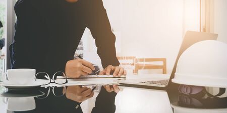 Image of engineer drawing plan on blue print in office near working site with panoramaの写真素材
