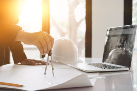 Engineer or Architect concept, Image of engineer drawing a blue print design building or house, An engineer workplace with blueprints, pencil, protractor and safety helmet, Industry conceptの写真素材
