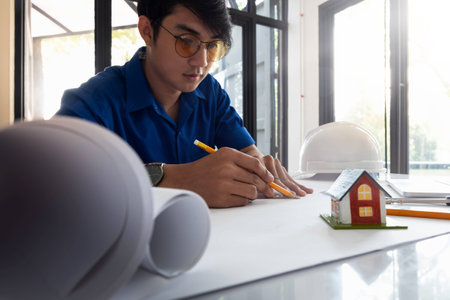 Architect man working drawing construction on blueprints, engineer inspection in workplace for architectural plan, sketching a construction projectの写真素材