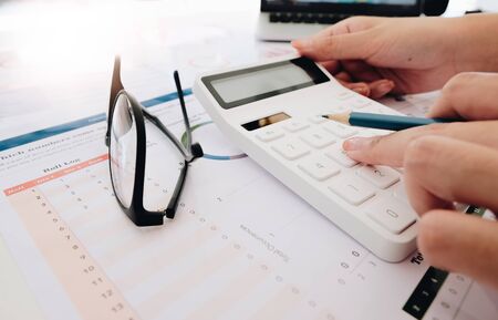 Close up Business woman using calculator and laptop for do math finance on wooden desk in office and business working background, tax, accounting, statistics and analytic research conceptの写真素材
