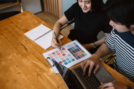 Group of young designers in casual clothes is using a laptop, discussing affairs.