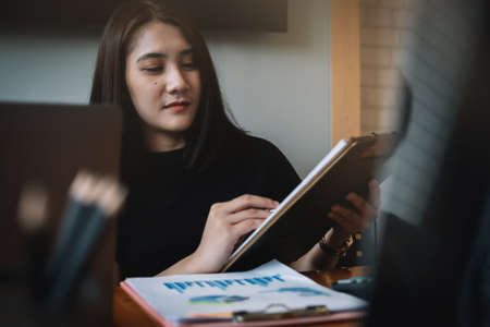 young businesswoman checking financial reports, economic graphs and charts at workplace, sitting at desk in office.の写真素材