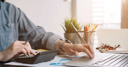 Close up businessman or accountant working using calculator with financial report and calculator