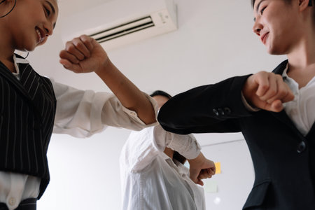 Group of business greeting bumping elbows at workplace, happy coworkers in medical facial covers protect from  pandemics, healthcare concept.の写真素材