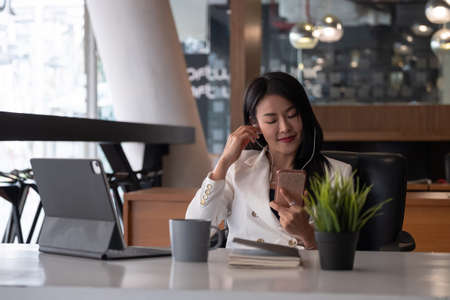 Relax Time - Businesswoman with headphones sitting at the desk indoors in officeの写真素材