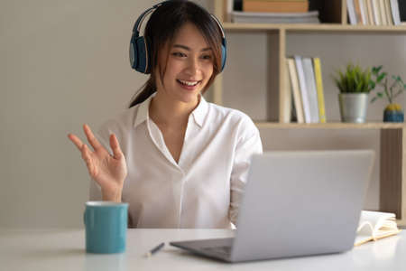 Beautiful asian woman in headphones have video call distant class with teacher using laptop - Online learning concept.の写真素材
