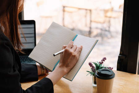 Close up of woman hold pen writing making notes in notebook studying at home, female handwrite in book, take educational course or training, seminar, education concept.の写真素材