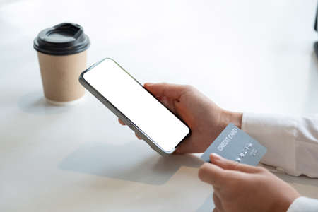 Close up hand of woman shopping online with credit card using smart phone at cafe