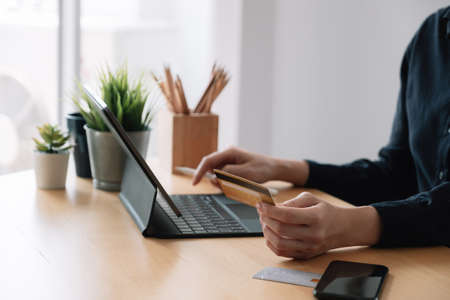 Close up hand of woman making online payment using laptop for shopping at home.の写真素材