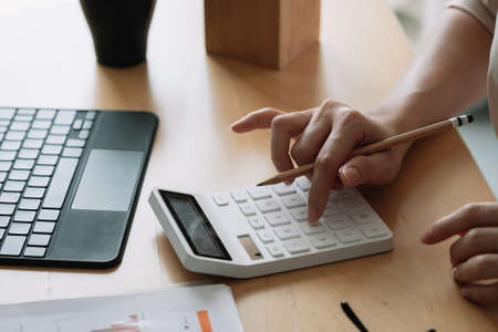 Close up Business woman or accountant using calculator with computer laptop, Business accounting, budget and loan paper at homeの写真素材